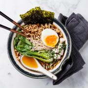 Bowl of ramen noodles in broth with eggs, seaweed and bok choy