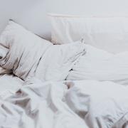 Photo of pillows and sheets on a recently slept-in bed.