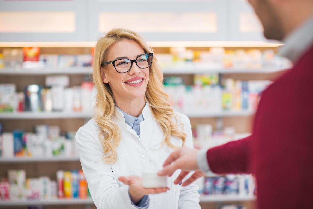 Photo of a pharmacist handing a patient a box of naloxone.