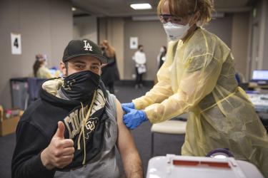 man in cu hat and sweatshirt giving a thumbs up as he gets the vaccine