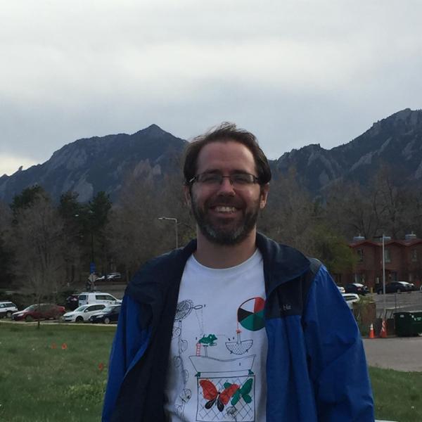 Matthew Jacobs stands in front of the Flatirons.