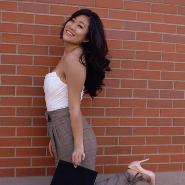 Jasey Kim stands in front of a brick wall.