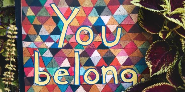 Colorful triangle-patterned background with "You belong" written on it
