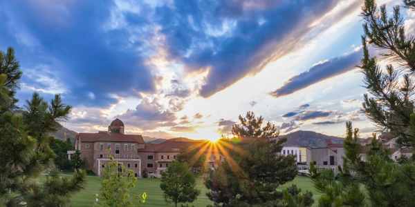 sun peaking out above buildings on main campus