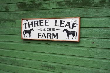 'Three Leaf Farm Est. 2010' sign on side of green building