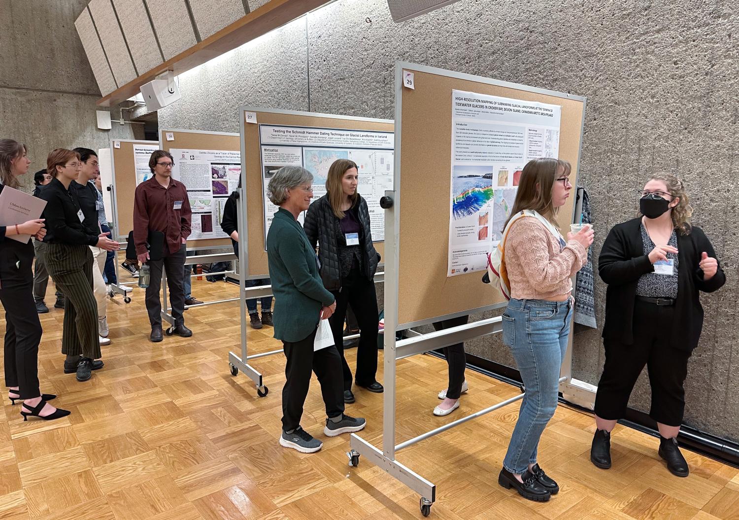 Groups of polar researchers cluster in groups around a series of science posters at the 52nd Arctic Workshop, discussing methods and results.