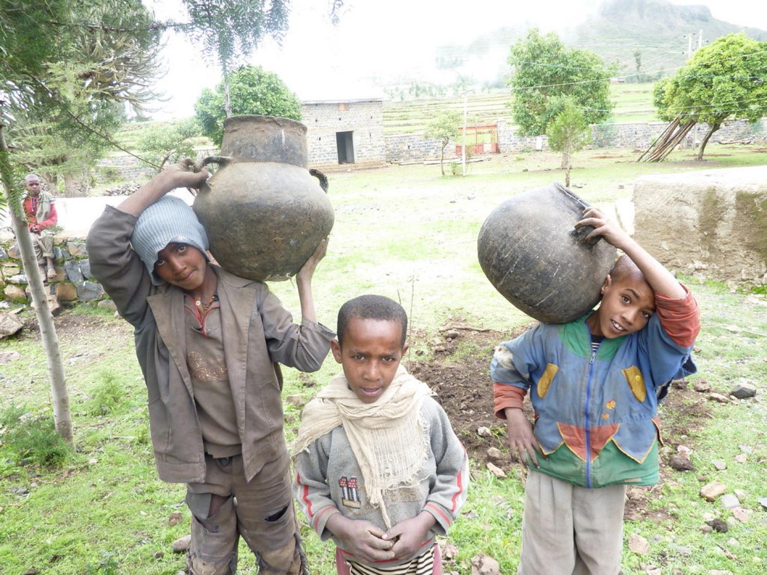 Several Ethiopian boys pose while holding giant clay pots to be planted for fruits and vegetables