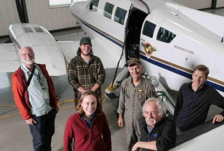 Atmospheric researchers stand next to their research airplane