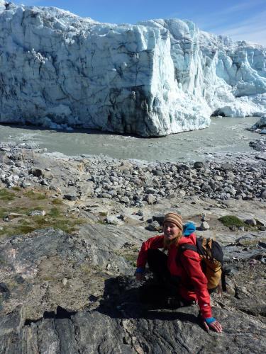 Irina Overeem sits near a rocky meltwater stream alongside steep ice cliffs of the Greenland Ice Sheet margin