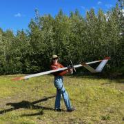 CU Boulder incoming PhD student Paloma Siegel carries an autonomous aircraft (~10 foot wingspan) away from an Alaskan landing strip after a flight 
