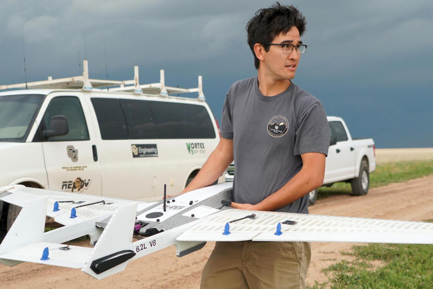 A student holding the drone in the field