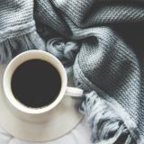 Image of a cup of coffee with a blanket next to it