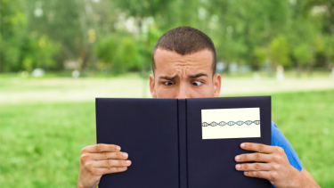 man reading a book of DNA and looking confused