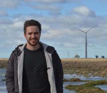 William Radünz smiling with wind turbine in the background