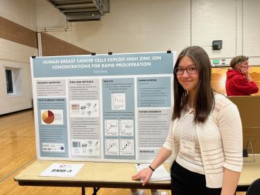 Kylie Berg standing next to her poster at the Colorado Science and Engineering Fair. Her poster is titled "Human breast cancer cells exploit high zinc ion concentrations for rapid proliferation."