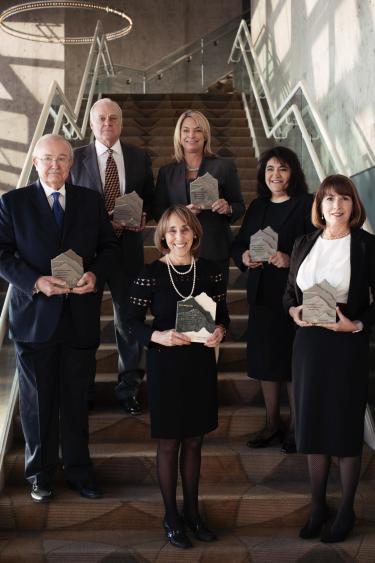 Honorees stand on a staircase displaying their alumni awards