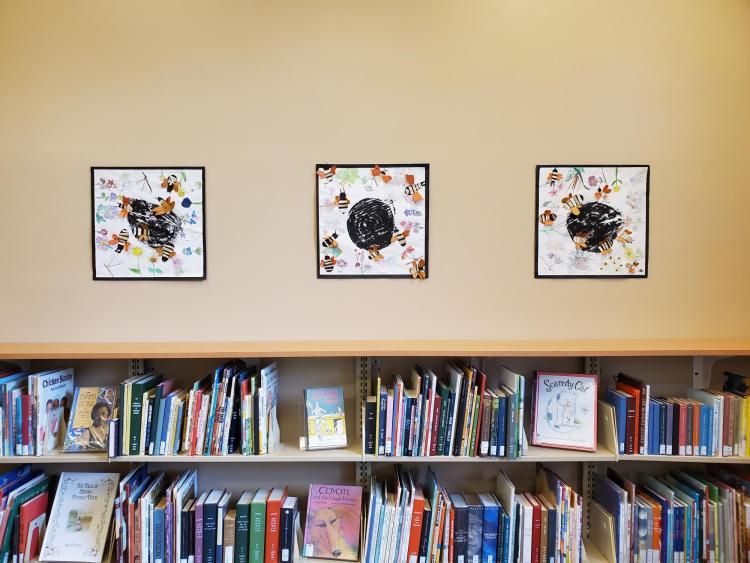 Students from University Hill Elementary School bee designs hang on wall. 