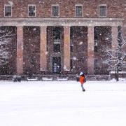 A student walking in front of Norlin on a snowy day