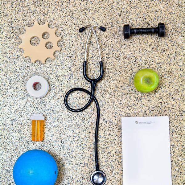 Photo including items from Wardenburg Health Center (gear, stethoscope, pill bottle, tape, apple, notepad, weight) (Photo by Patrick Campbell/University of Colorado)