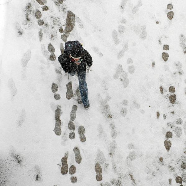 Aerial view of student walking on snowy path. 