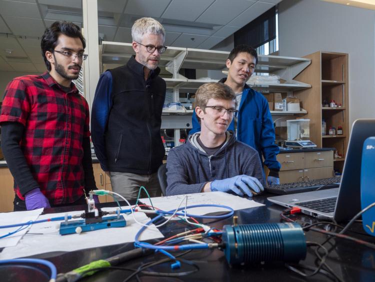 Mike McGehee in a lab with three students at a computer.