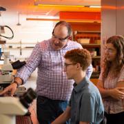 A faculty member working with two students in a lab.