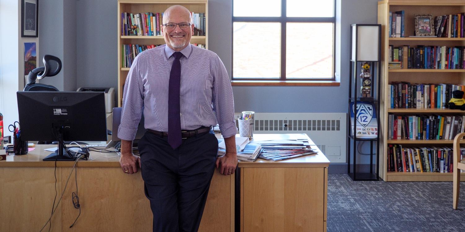 John Davis leaning on desk in his office