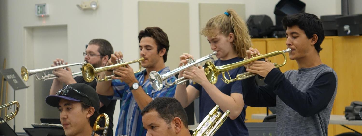 Four trumpet students playing in ensemble rehearsal