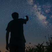 Photo of a person holding up a cell phone, night sky in background