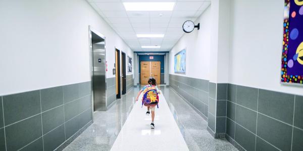 A boy running down the hall at school