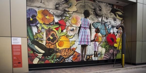 Mural by Lares Feliciano of young girl of color looking at flowers