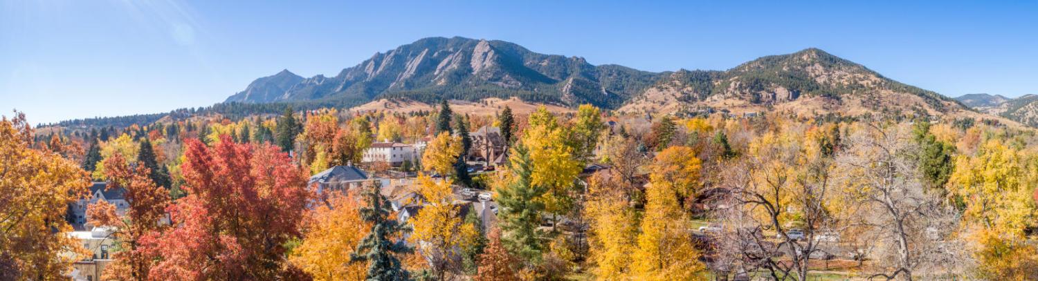 Photo of campus in the fall with the flatirons in the background.