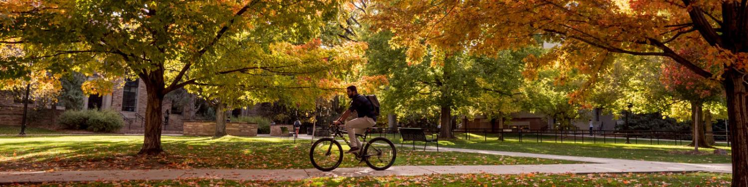 Student riding on a bike through campus