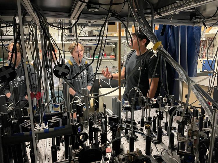 REU students speak with a researcher in a physics lab