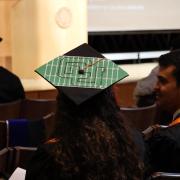 A student wearing a graduation cap with the CU interlocking logo decorated on top