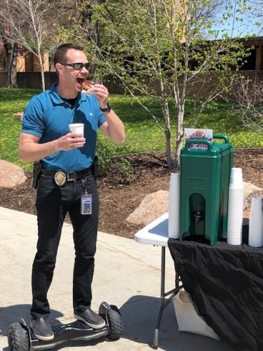 An officer eating a donut and drinking coffee while riding a hover board
