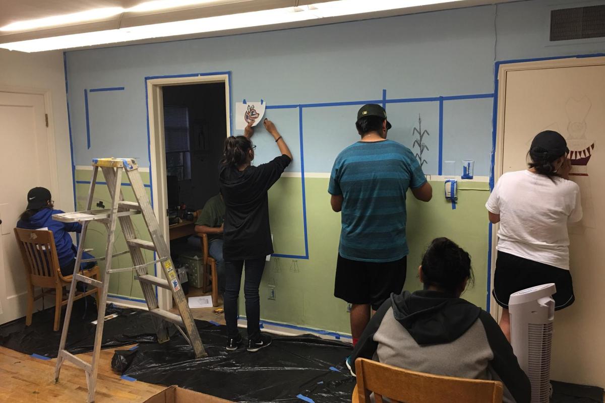 students painting artwork on a wall together