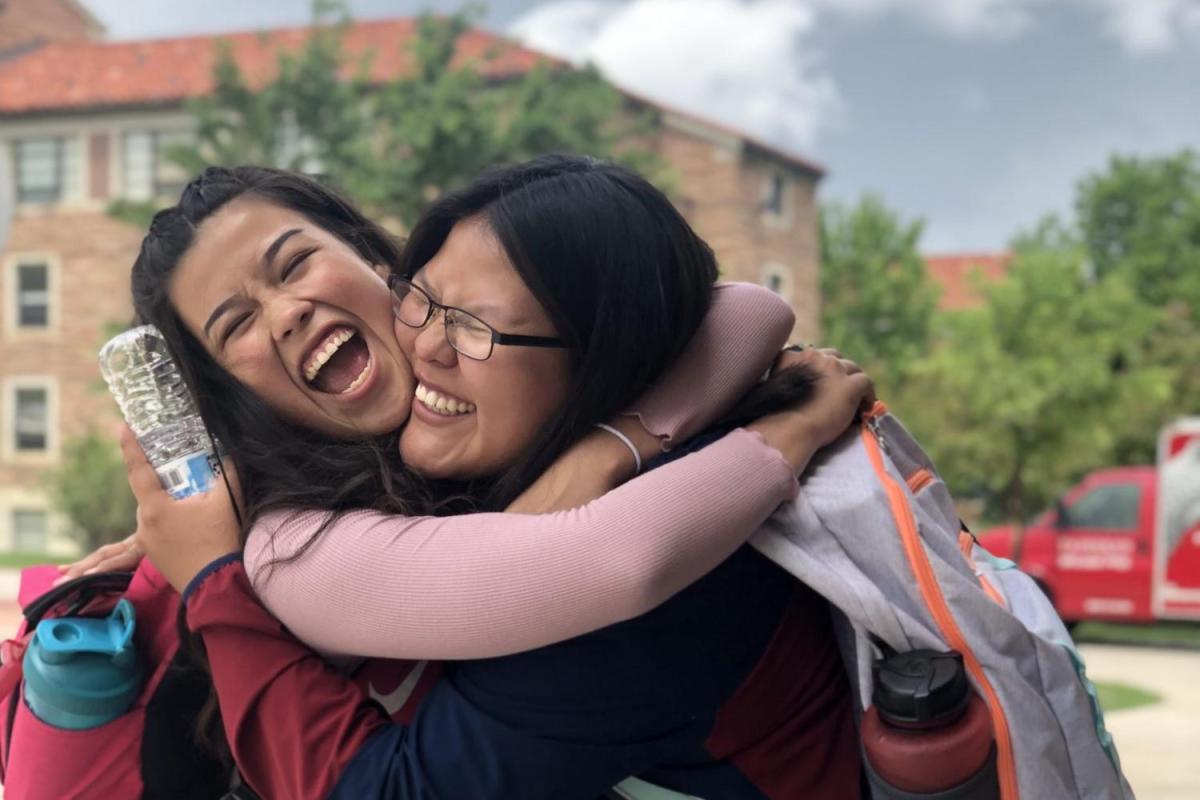 two CUUB students smiling and hugging each other