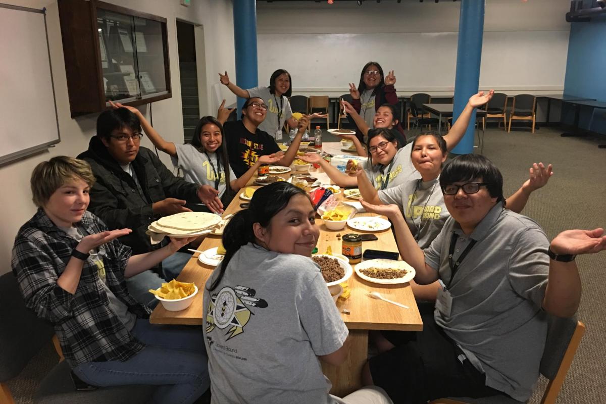 students eating a meal together and raising their arms up
