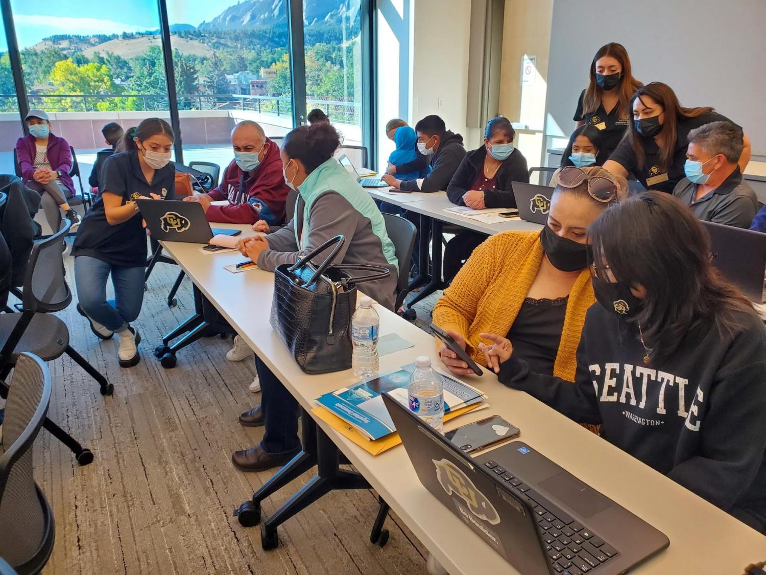 a group of parents and students fill out financial aid applications during a Saturday Academy