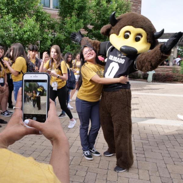 a student posing with Chip the buffalo, CU's costumed mascot