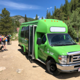 Green bus in front of hikers on a hiking trail