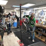Two bike mechanics perform maintenance on bikes.