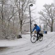 Person riding bicycle on multi-use path in snowy conditions.