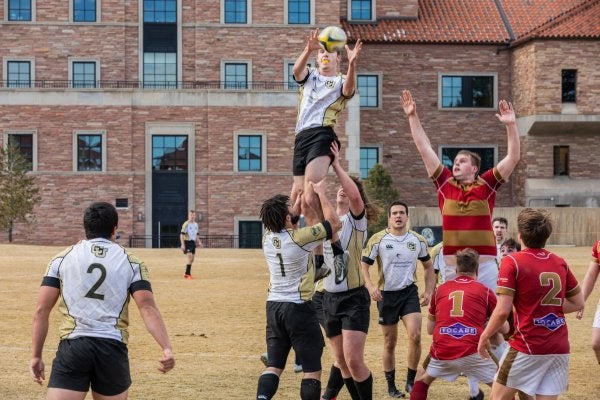 Men's rugby team throwing player in air