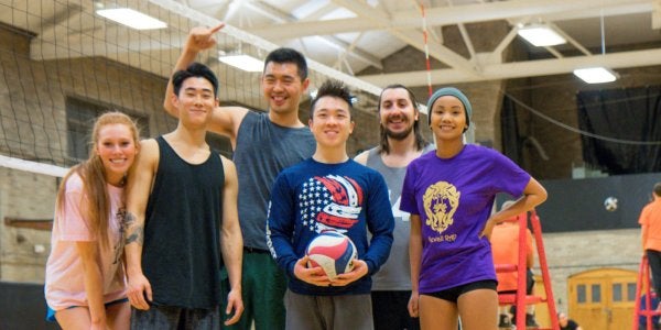 group of students posing next to a volleyball net