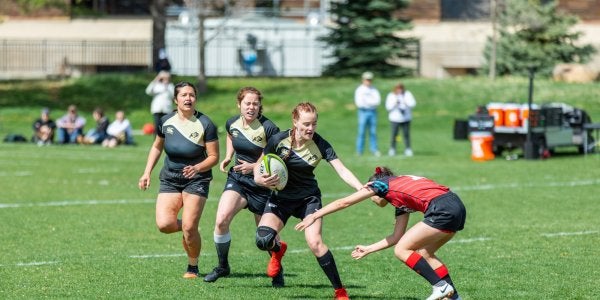 Women's rugby team deflecting a tackle