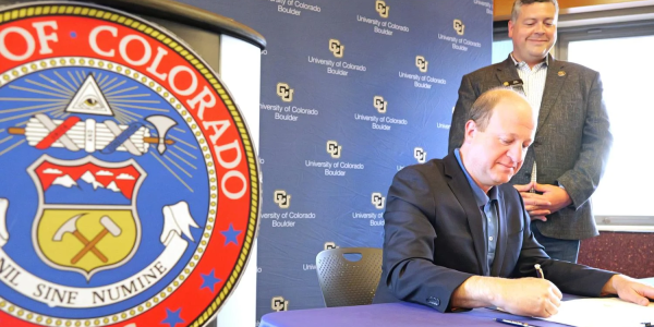 Gov. Jared Polis signs HB24-1325 into law while Representative Alex Valdez looks on. (Credit: Casey Cass/CU Boulder)