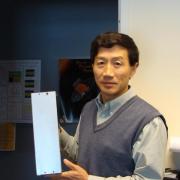 CU Boulder Professor Xinlin Li holds up a model of the CSSWE cube satellite