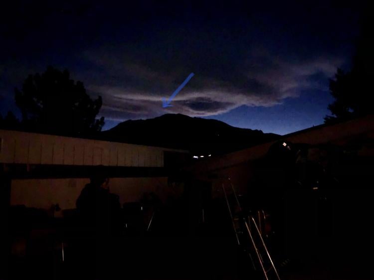 Photo from the view of the observing deck with a 20" PlaneWave telescope, cloud and a little bright spot above the Flatirons with an arrow pointing to the conjunction.